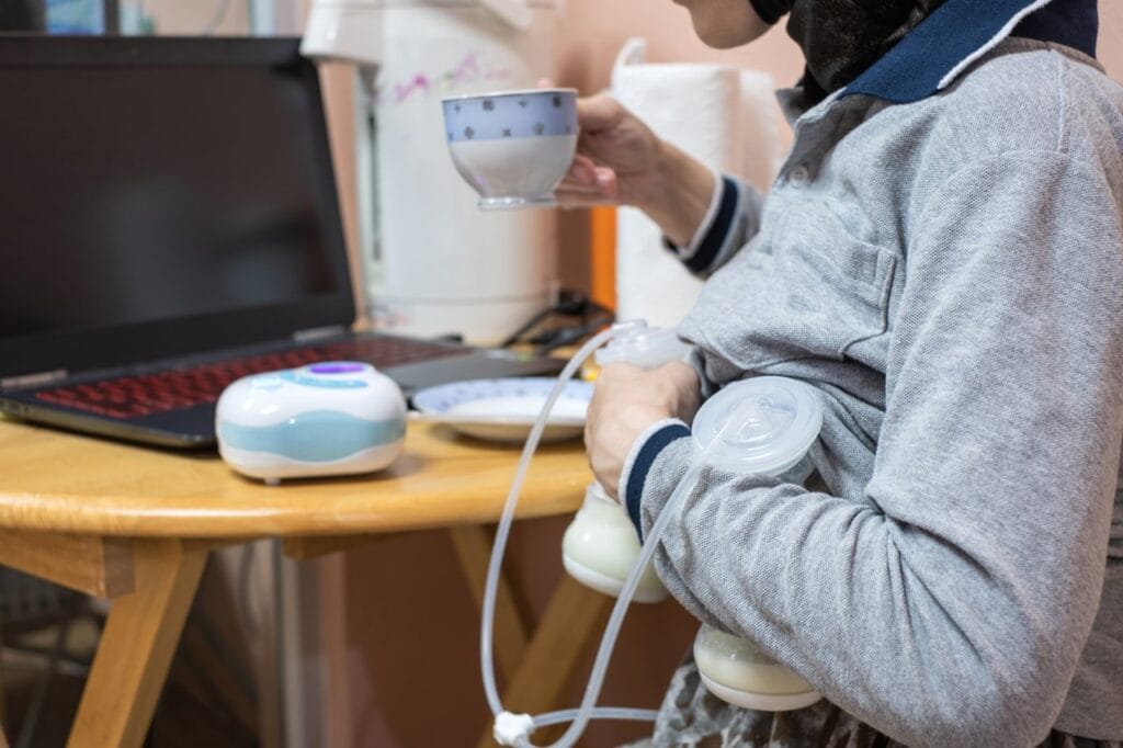 mamă alăptând și folosind pompă electrică, bând ceai pentru stimularea lactației, creșterea rapidă a producției de lapte