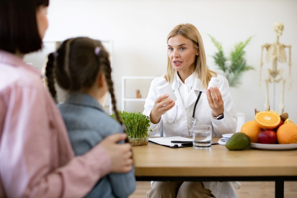 discuție între medic, copil și părinte despre vitaminele recomandate pe grupe de vârstă
