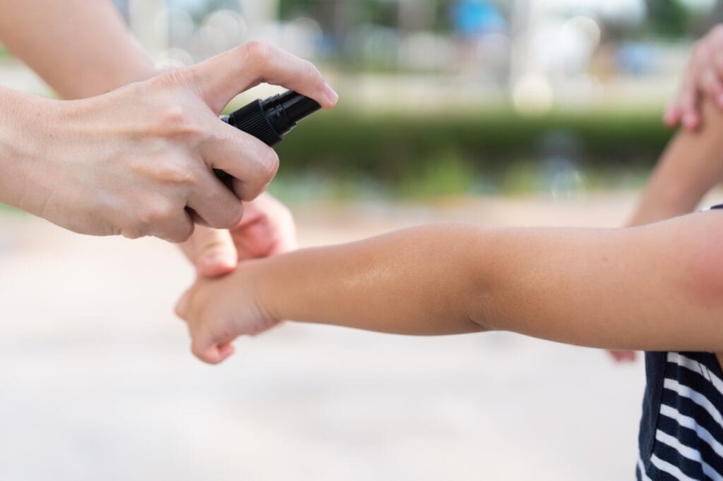 aplicare spray anti-țânțari pe pielea copilului pentru protecție eficientă împotriva țânțarilor