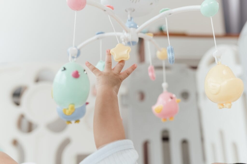 bebeluș atinge carusel pătuț jucării colorate stimulare vizuală dezvoltare motrică