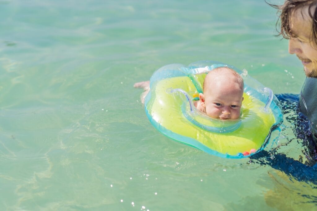 bebeluș în colac de gât plutind în apă alături de adult, diferențe colac gât vs colac clasic