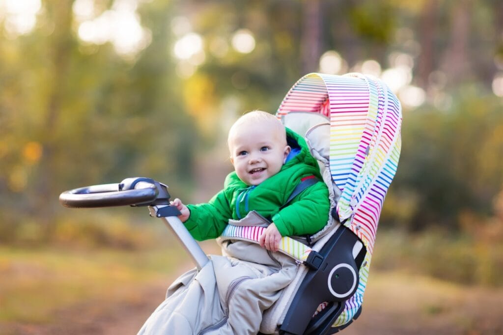 Bebeluș zâmbitor în cărucior cu sac de dormit antialergic, protecție pentru pielea sensibilă