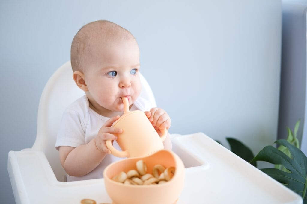 Bebeluş folosind o cană cu pai din silicon alimentar bebeluș bea din cană cu pai silicon alimentar, fără BPA, siguranță hidratare copii mici