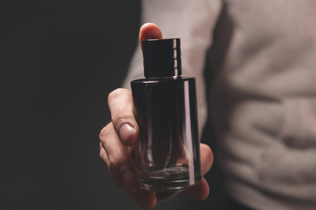 sticlă de parfum bărbătesc ținută în mână, ideală pentru birou sau ieșire în oraș
