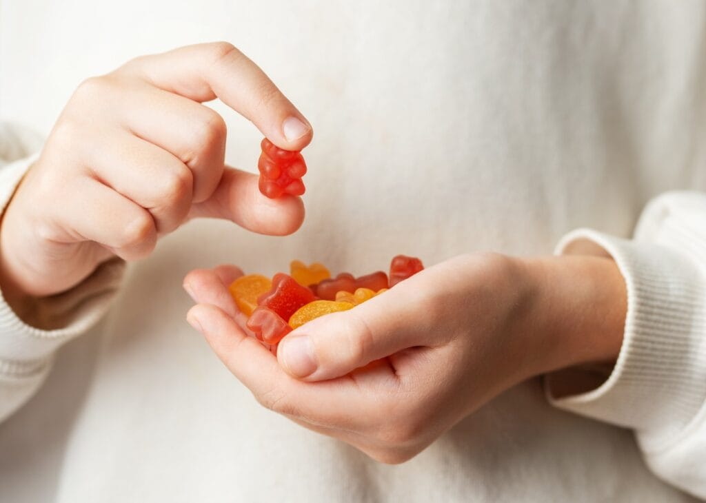 Jeleurile pentru imunitate la copii: atracție sau reală eficiență? copil ține jeleuri vitaminizate în mână, suplimente pentru imunitate și multivitamine tip gummy