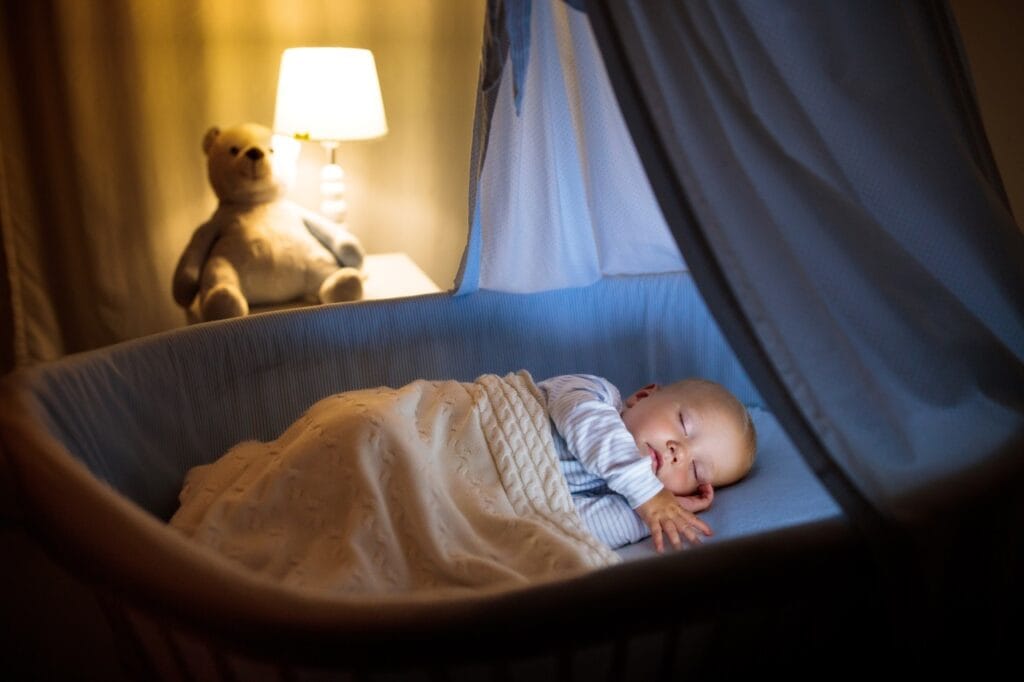 Bebeluș dormind sub baldachin, cu pătuț și lumini ambientale, idei de accesorii pentru camera copilului