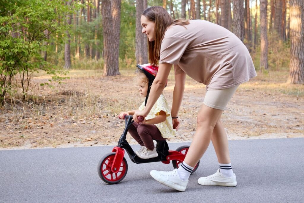 Învață să iubească bicicleta fără pedale, pas cu pas adult ajută copil să folosească bicicleta fără pedale într-un parc, învățare echilibru