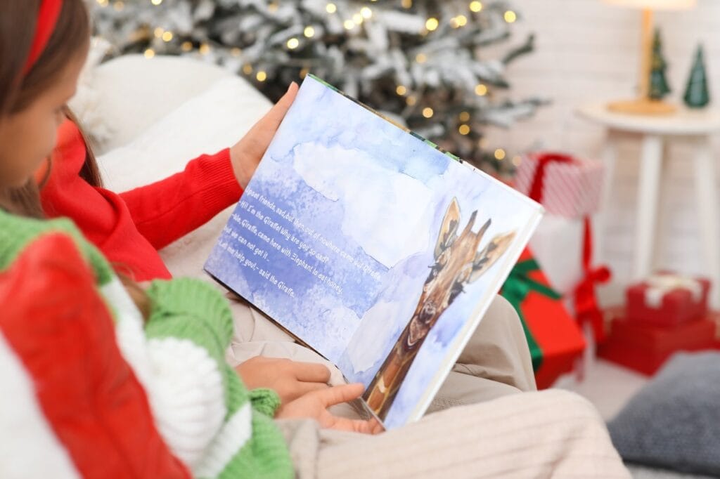 Fetiță citind o carte ilustrată de povești pentru copii în fața bradului, evidențiind importanța ilustrațiilor