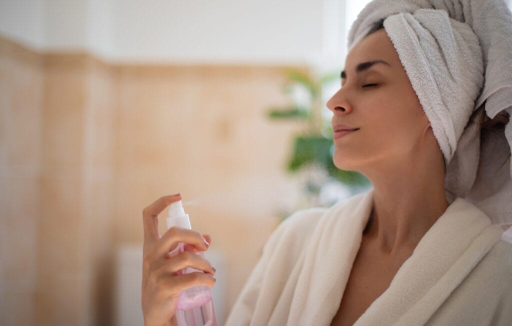 femeie folosind apă termală pe ten, ritual zilnic recomandat de dermatologi pentru calmarea pielii sensibile