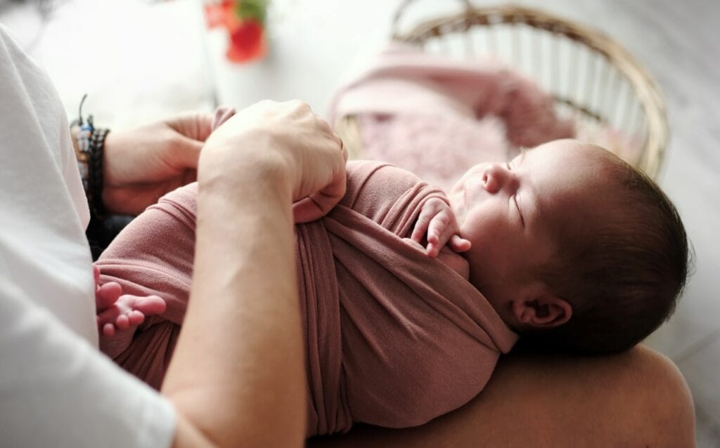 Bebeluș mic înfășat în pătură roz, instrucțiuni pentru folosire corectă