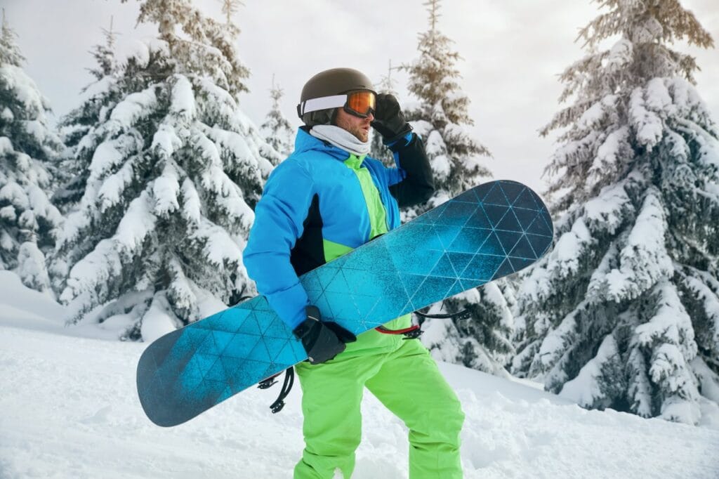 Accesorii esențiale pentru o zi reușită pe pârtia de snowboard snowboarder echipat cu geacă tehnică și accesorii utile pe pârtie, printre brazi acoperiți de zăpadă