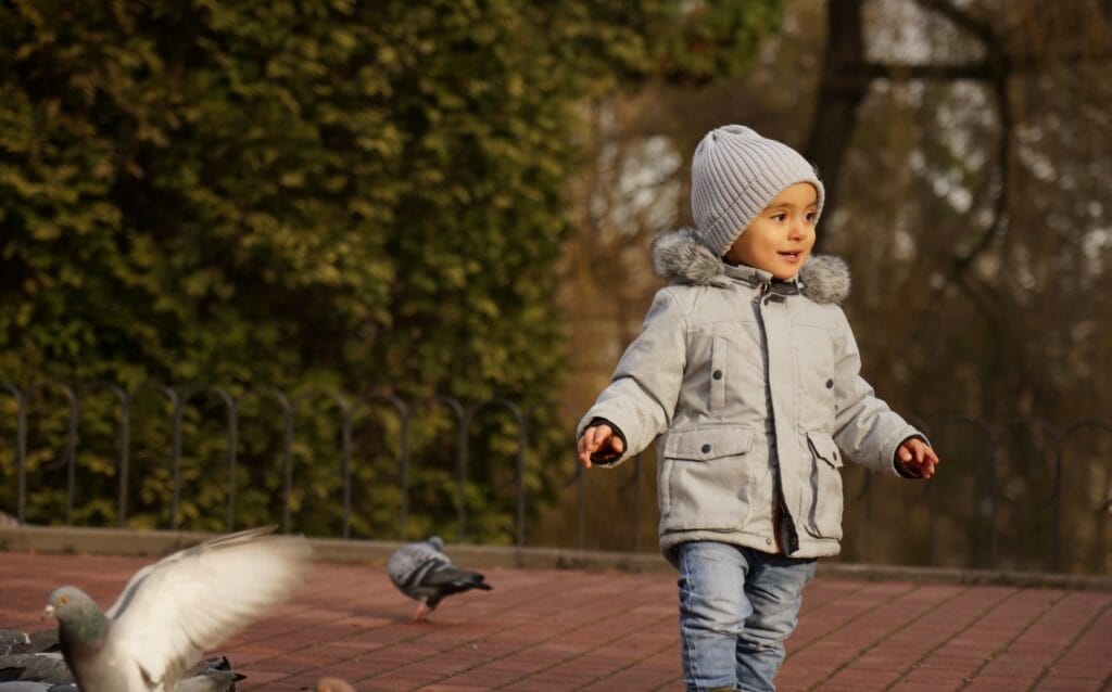 copil îmbrăcat cu geacă de iarnă respirabilă, joacă în aer liber, confort termic
