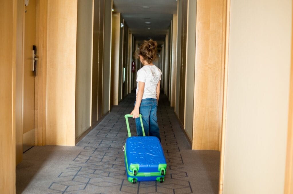 copil trăgând un troler cu funcții smart pentru copii pe holul unui hotel