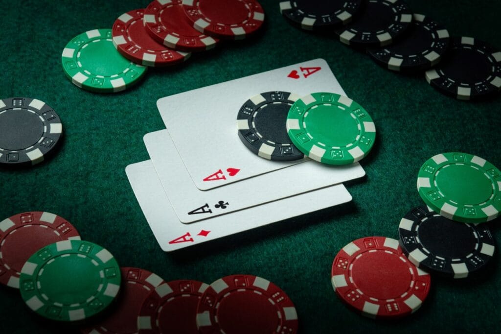 jetoane de poker așezate pe masă verde alături de cărți de joc pentru o seară de poker reușită