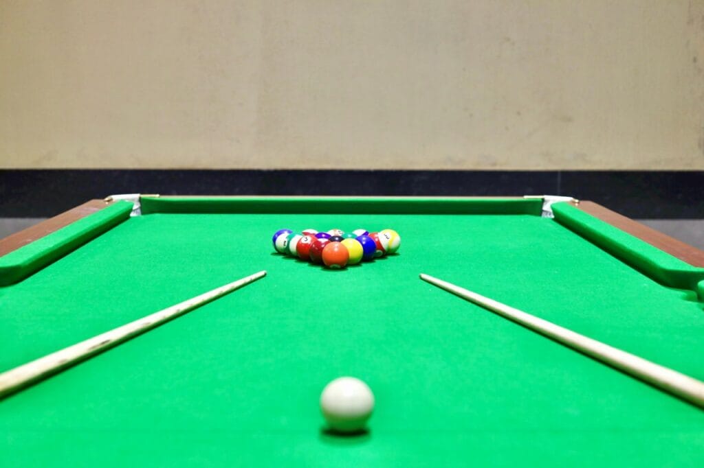 masă de biliard indoor cu suprafață textilă verde, ilustrând diferența față de mesele outdoor