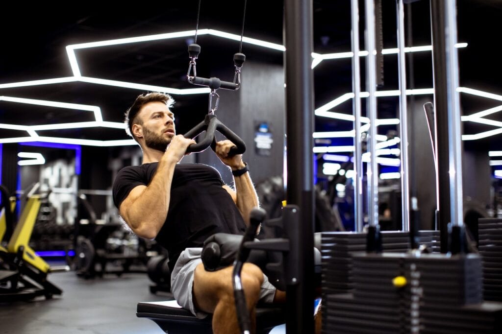 bărbat executând exercițiu corect la aparat multifuncțional fitness, reguli de siguranță la antrenament